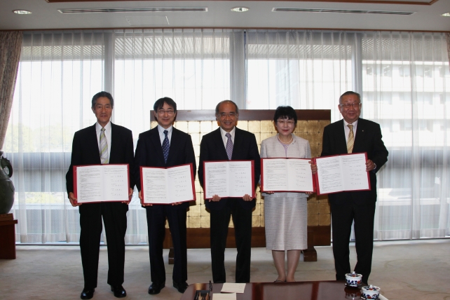 協定書を手に記念撮影を行う出席者 左から平居日本文理大学長，北野大分大学長，広瀬大分県知事，村嶋県立看護科学大学長，豊田別府大学長